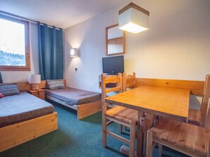 A cozy room with a wooden bed, a small sofa, a wooden table, and a television.
