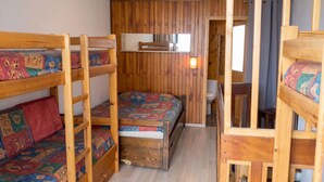 A bunk bed room with a wooden floor, a small desk, and a window with curtains. - Homerez - Apartment in Les Menuires. (Les Menuires)