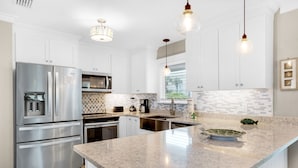 A modern kitchen with white cabinetry, stainless steel appliances, a granite countertop, and pendant lighting. - Beach Svc⛱️PrivatePool-Gulf Views-Crows Nest-Windancer Amenities-3BR Sun☀️Seeker (Miramar Beach)