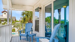 A covered porch with blue Adirondack chairs and a view of a swimming pool. - Beach Svc⛱️PrivatePool-Gulf Views-Crows Nest-Windancer Amenities-3BR Sun☀️Seeker (Miramar Beach)