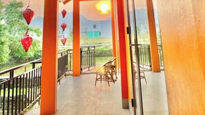 Un espace extérieur abrité, avec des murs orange, une porte en verre et une vue sur le paysage.