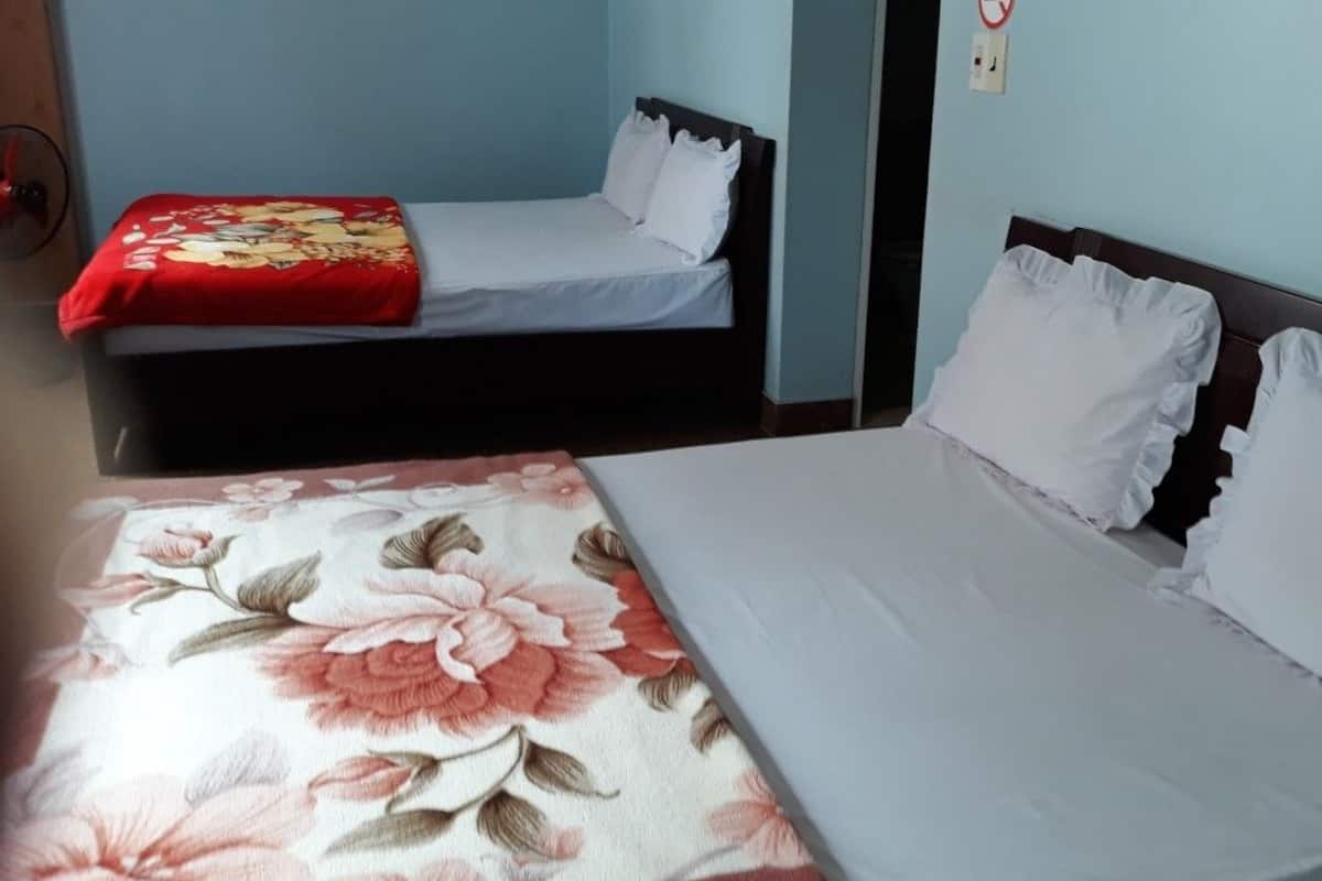 Ein Zimmer mit zwei Betten, eines mit einem blumigen Überwurf und das andere mit schlicht weißer Bettwäsche.