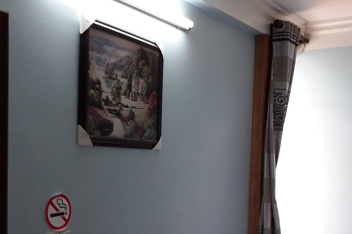 Ein Hotelzimmer mit Bett, Nachttisch mit Lampe, einem Bild an der Wand und einem Rauchverbot-Schild.