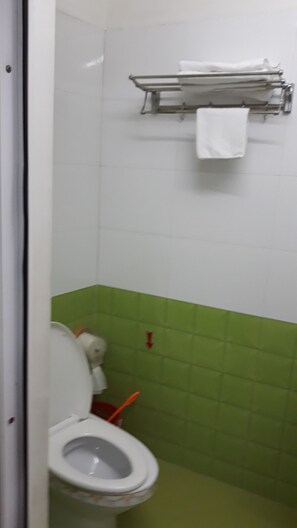 A bathroom with a toilet, green tiles, a towel rack, and a red arrow on the wall. - Kim Thoa Motel (Hai Phong)