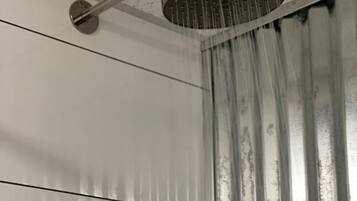 A shower with a rain-like water feature, a metal pipe, and a curtain.