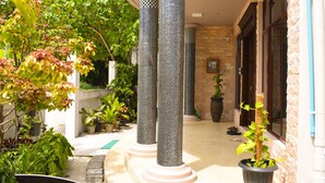 A courtyard with tall columns, potted plants, and a stone wall.