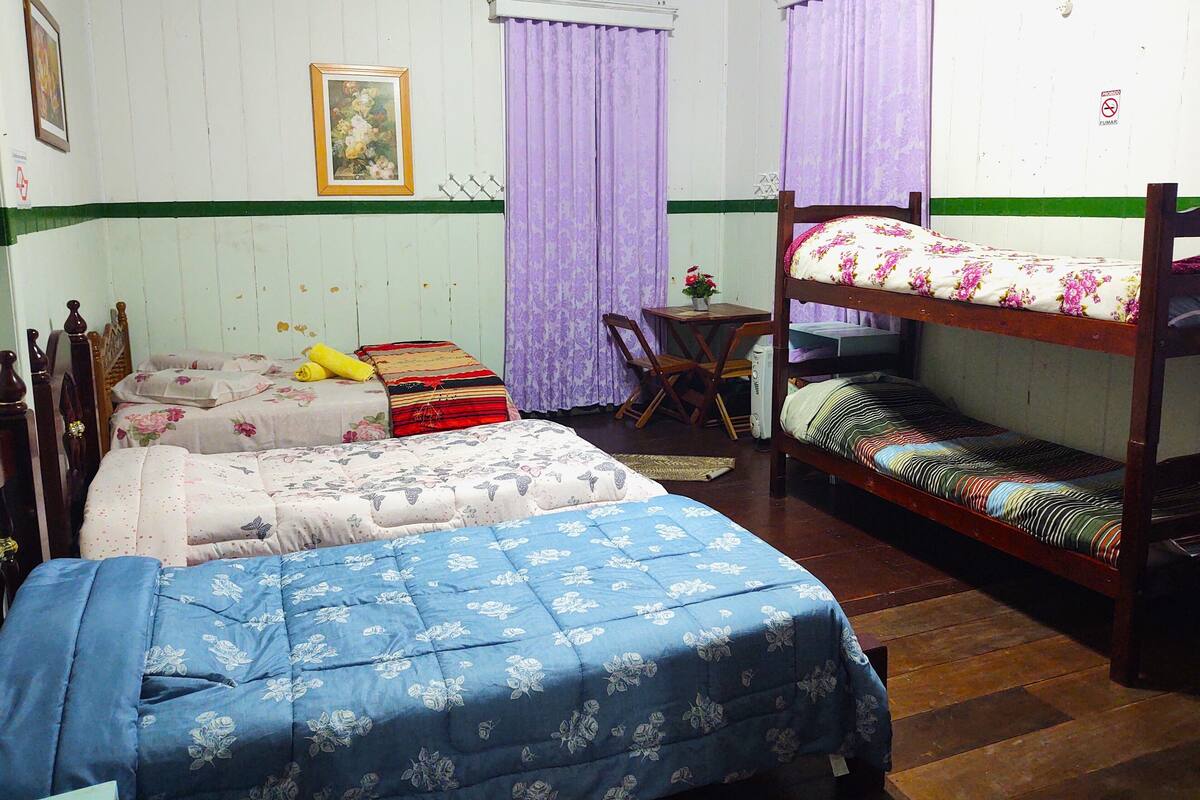 A room with bunk beds, a small table with a chair, and a bed with a floral bedspread.