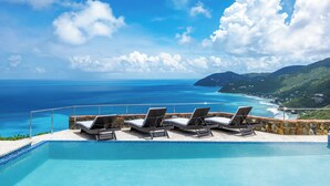 Una piscina amb gandules i vista a l'oceà i les colines.
