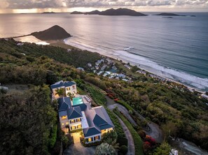 A coastal property with a swimming pool, multiple houses, and a view of the sea and islands.