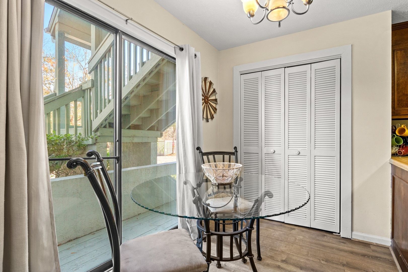 A dining area with a glass table, chairs, and a view of a staircase outside.