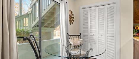 A dining area with a glass table, chairs, and a view of a staircase outside.