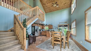 A spacious kitchen with wooden cabinets, a dining area with a table and chairs, and a staircase with a wooden railing. - Family Getaway on Douglas Lake! Home w/ Deck, View (Sevierville)