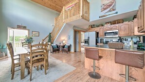 A spacious kitchen with wooden cabinets, a dining area with a wooden table and chairs, and a bar area with stools. - Family Getaway on Douglas Lake! Home w/ Deck, View (Sevierville)