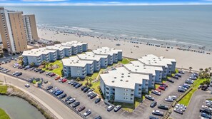 Ein Strandhotel mit mehrstöckigen Gebäuden, einem Parkplatz und einem Strand im Hintergrund.