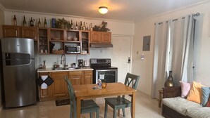 A compact kitchen with a refrigerator, microwave, stove, and dining table with chairs. - Comfy and Secure  One Bedroom Apt- Sleeps 3!! (New Kingston)
