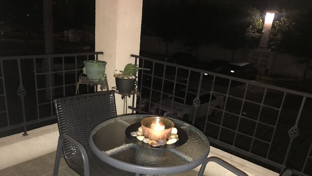 A balcony with a round table, two chairs, a candle, and potted plants. - Comfy and Secure  One Bedroom Apt- Sleeps 3!! (New Kingston)