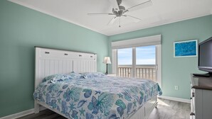 Ein Schlafzimmer mit Bett, Deckenventilator, Fenster mit Aussicht und Fernseher.
