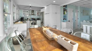 A spacious kitchen with white cabinetry, a wooden dining table, and a modern chandelier.