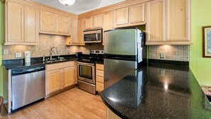 A modern kitchen with wooden cabinets, stainless steel appliances, and a black granite countertop. - Incredible Location - Just Moments from the Beach (Myrtle Beach)
