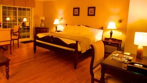 A hotel room with a large bed, two bedside lamps, a wooden nightstand, a small table with a lamp, and a chair. - St-Sauveur Lovely King Studio (Piedmont)
