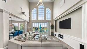 Un salon spacieux avec un grand canapé d’angle, une table basse et un téléviseur à écran plat fixé au mur.
