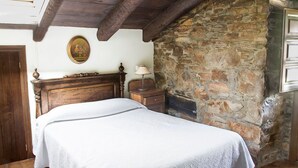 Een slaapkamer met een houten bed, een stenen muur, een houten plafond en een houten deur.
