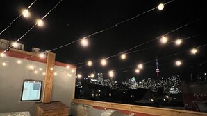 Una terraza en la azotea con luces colgantes, vistas de la ciudad y una cubierta de madera.