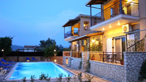 A multi-story building with a swimming pool, stone walls, and outdoor seating. - Alkionis (Lefkada)