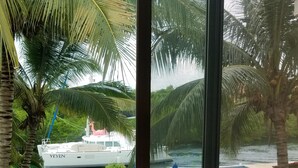 En vy över en yacht vid namn ”Yeyen” som ligger förtöjd nära en pool, med palmer och en gräsyta i bakgrunden.