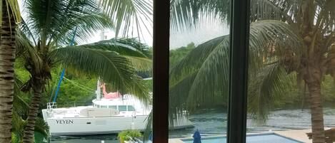 A view of a yacht named 'Yeyen' docked near a pool with palm trees and a grassy area.