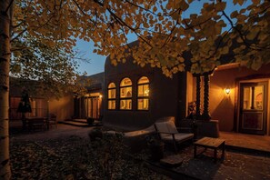 A building with arched windows and a patio area with outdoor furniture. - Casa Sara Adobe Home in Taos New Mexico, sleeps 12  (Arroyo Seco)