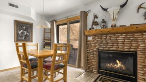 A cozy room with a stone fireplace, wooden dining table, and chairs.