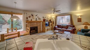 A cozy living room with a fireplace, a large window, a sofa, and a coffee table.