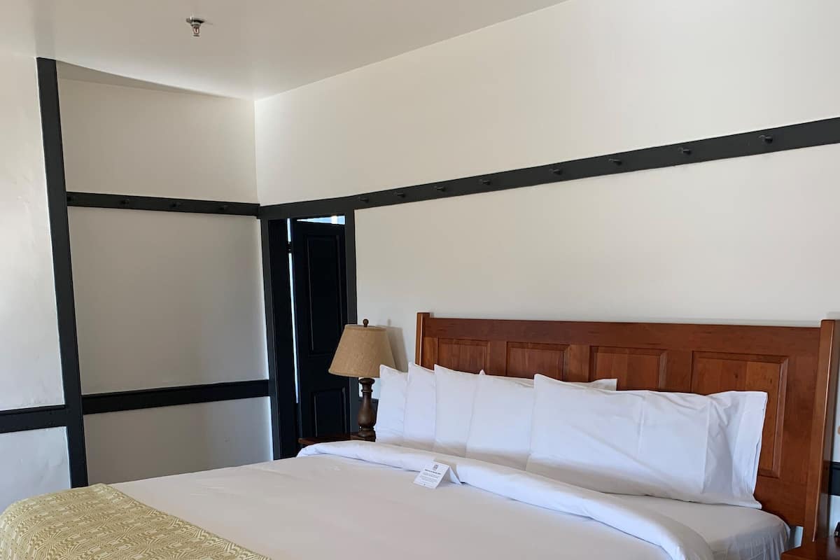 A neatly made bed with a patterned blanket, a wooden headboard, and a bedside lamp.