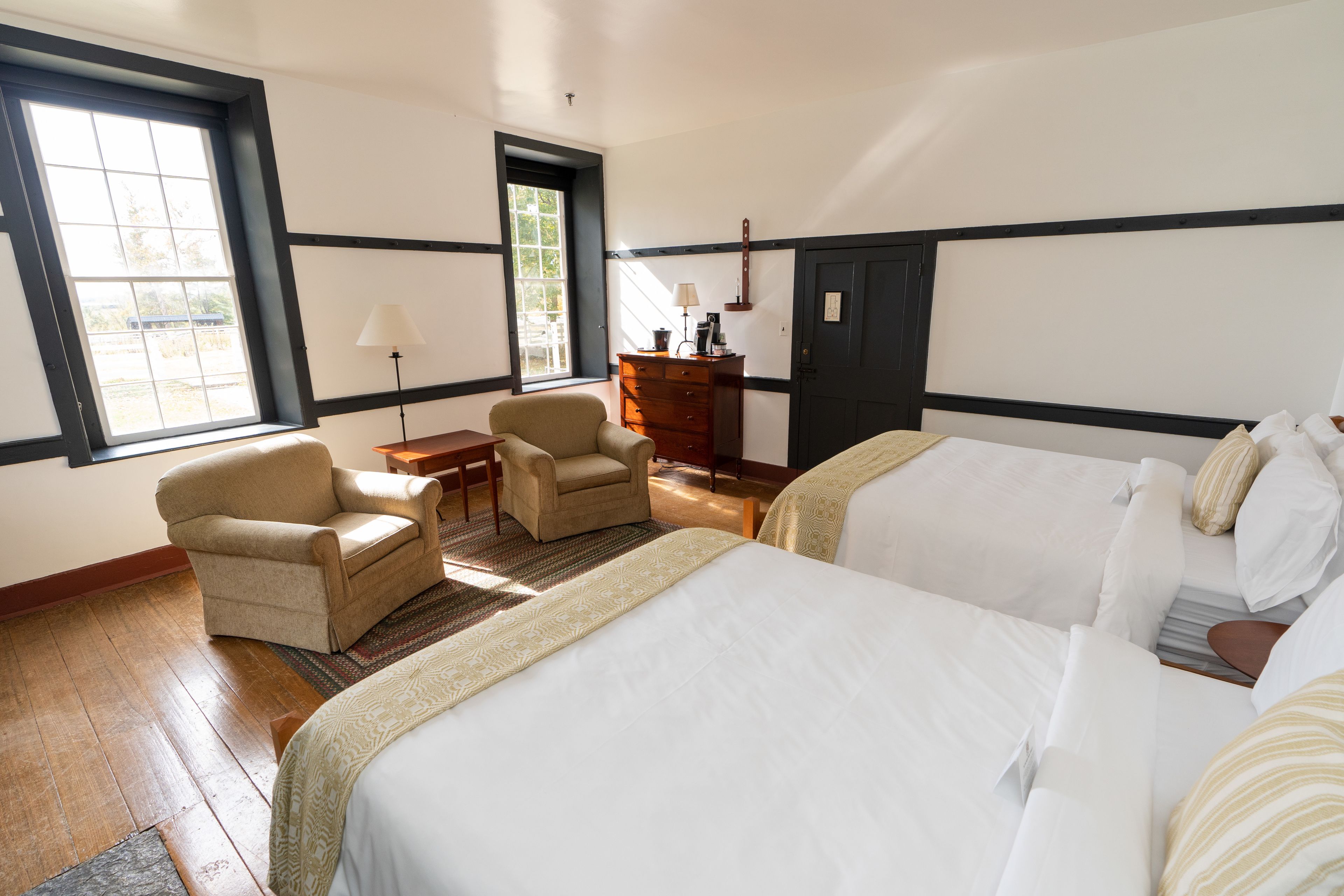 Habitación de hotel con dos camas, una silla, un tocador y una ventana.