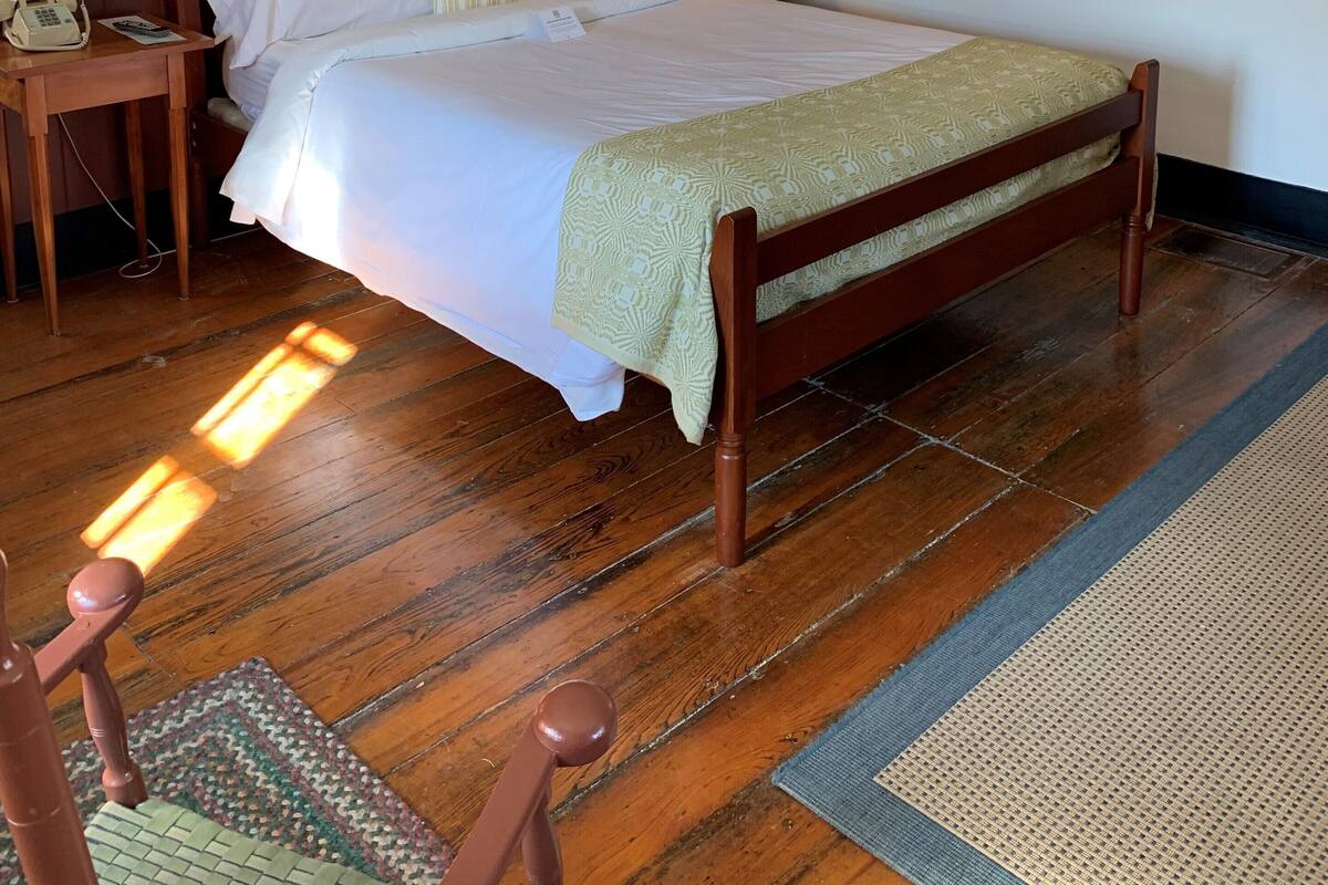 A neatly arranged hotel room with a wooden bed, a bedside table with a lamp, and a telephone.