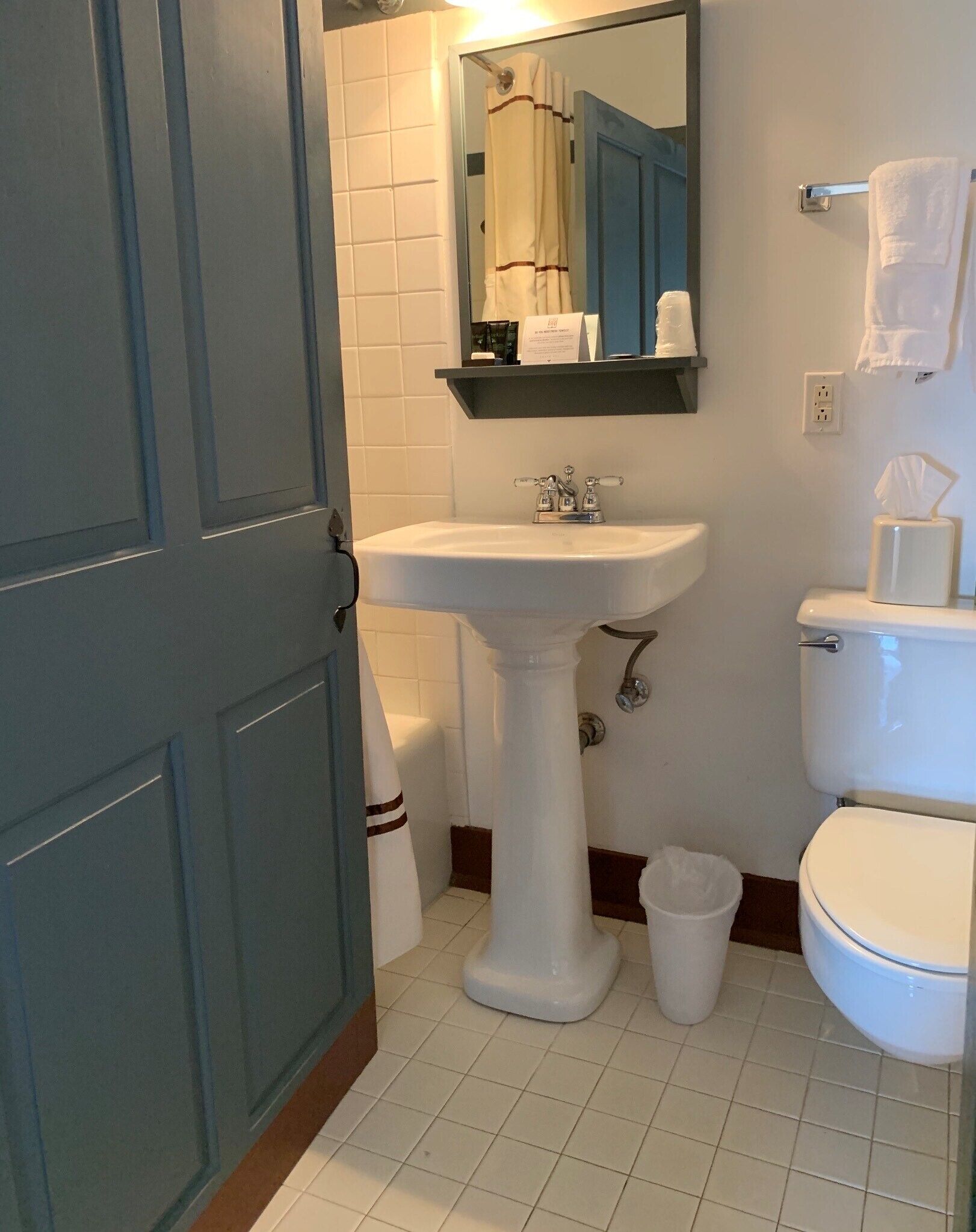A bathroom with a pedestal sink, toilet, and a mirror above the sink.