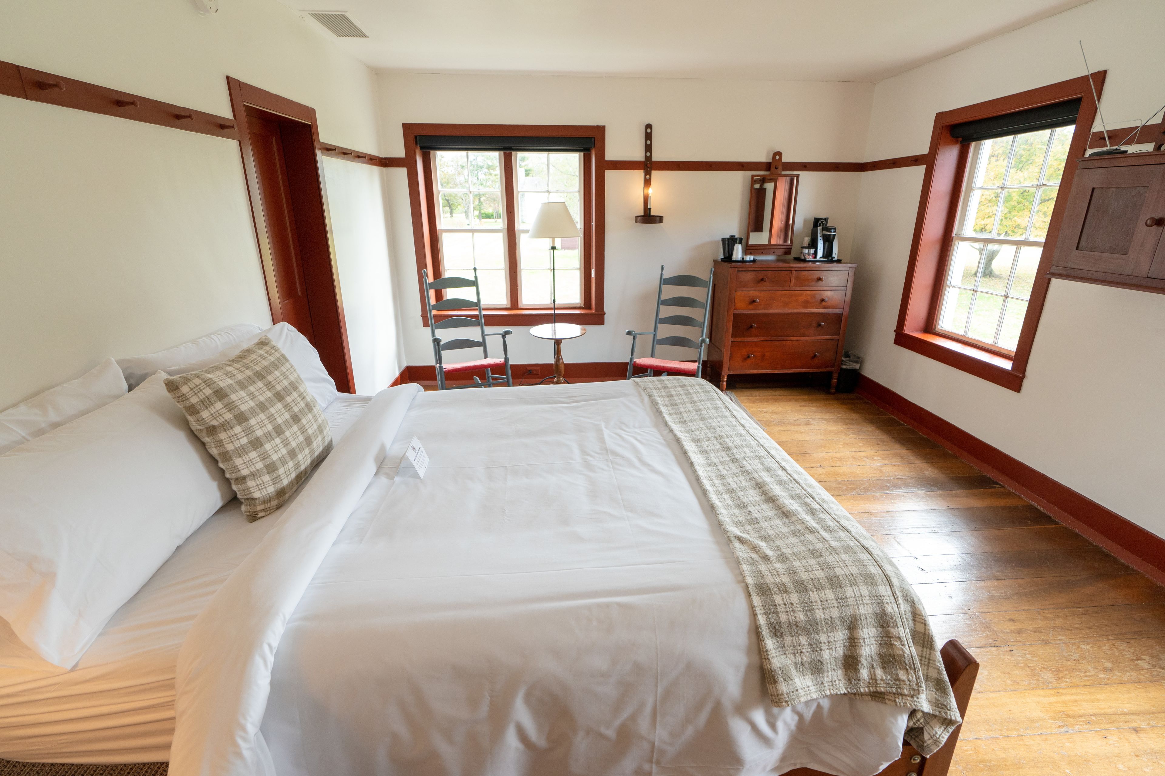 A bedroom with a large bed, a dresser, a desk, and two chairs.