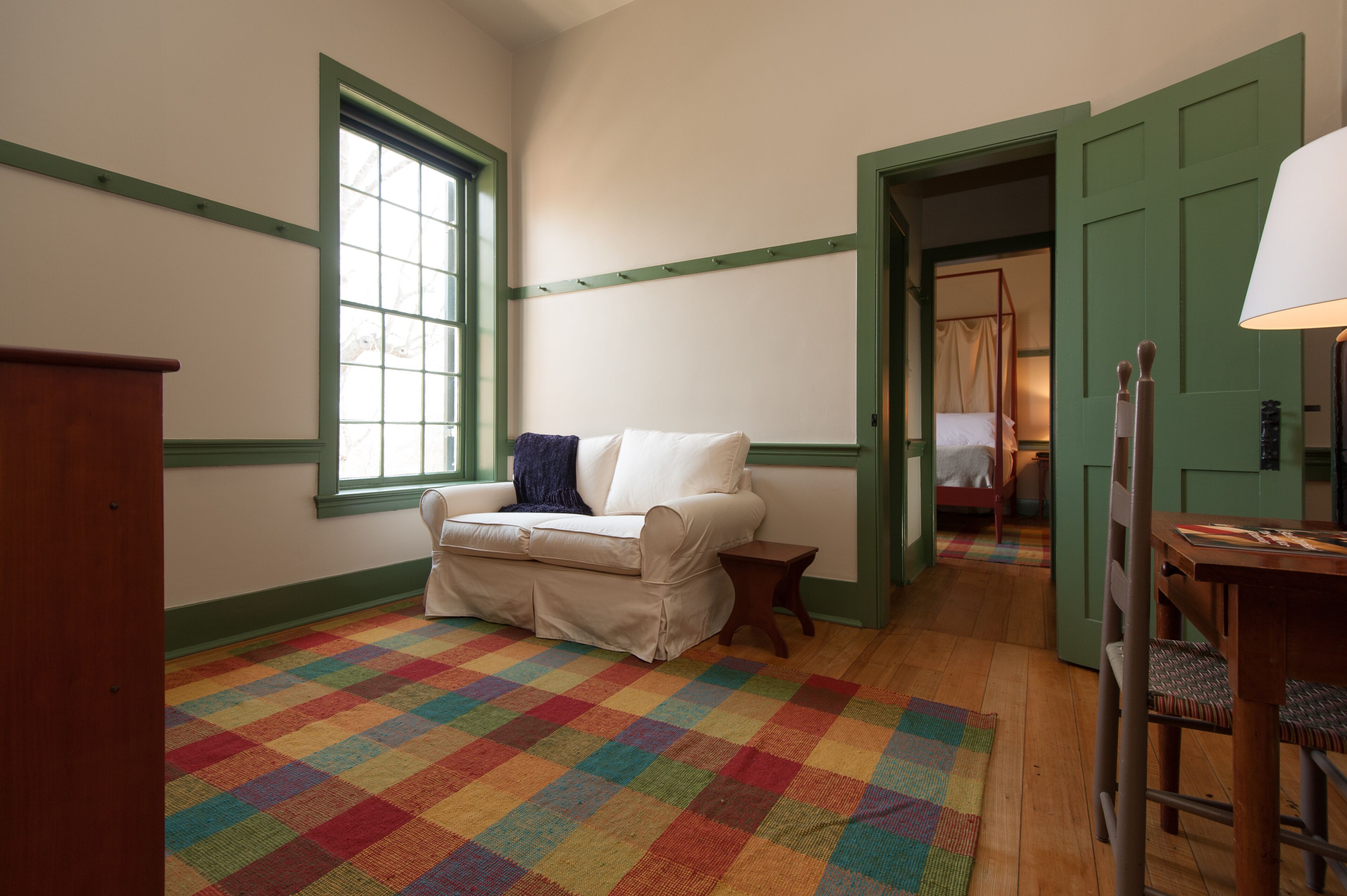 Una habitación con alfombra a cuadros, un sofá, una mesita y una silla.
