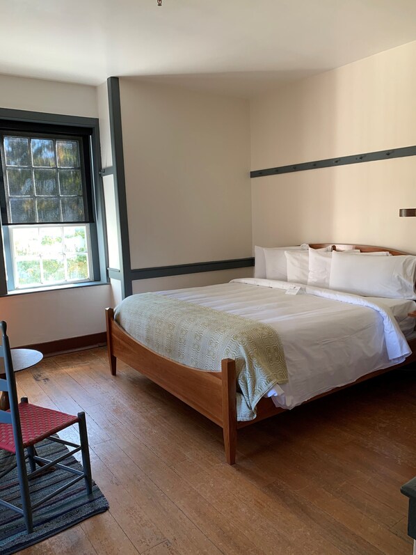 A bedroom with a wooden bed, a window with a view, and a chair.