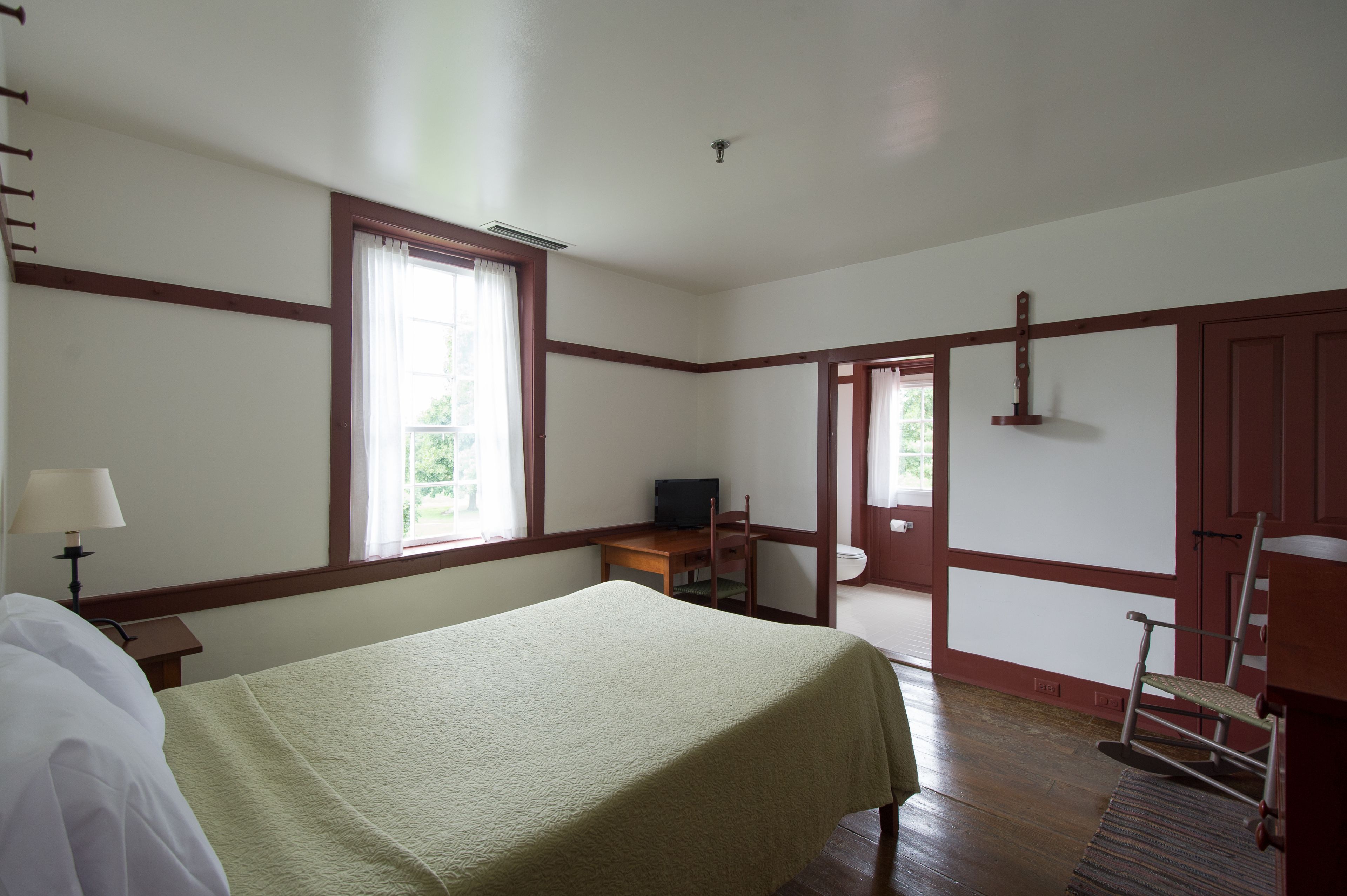 A room with a bed, a desk, a chair, and a television.