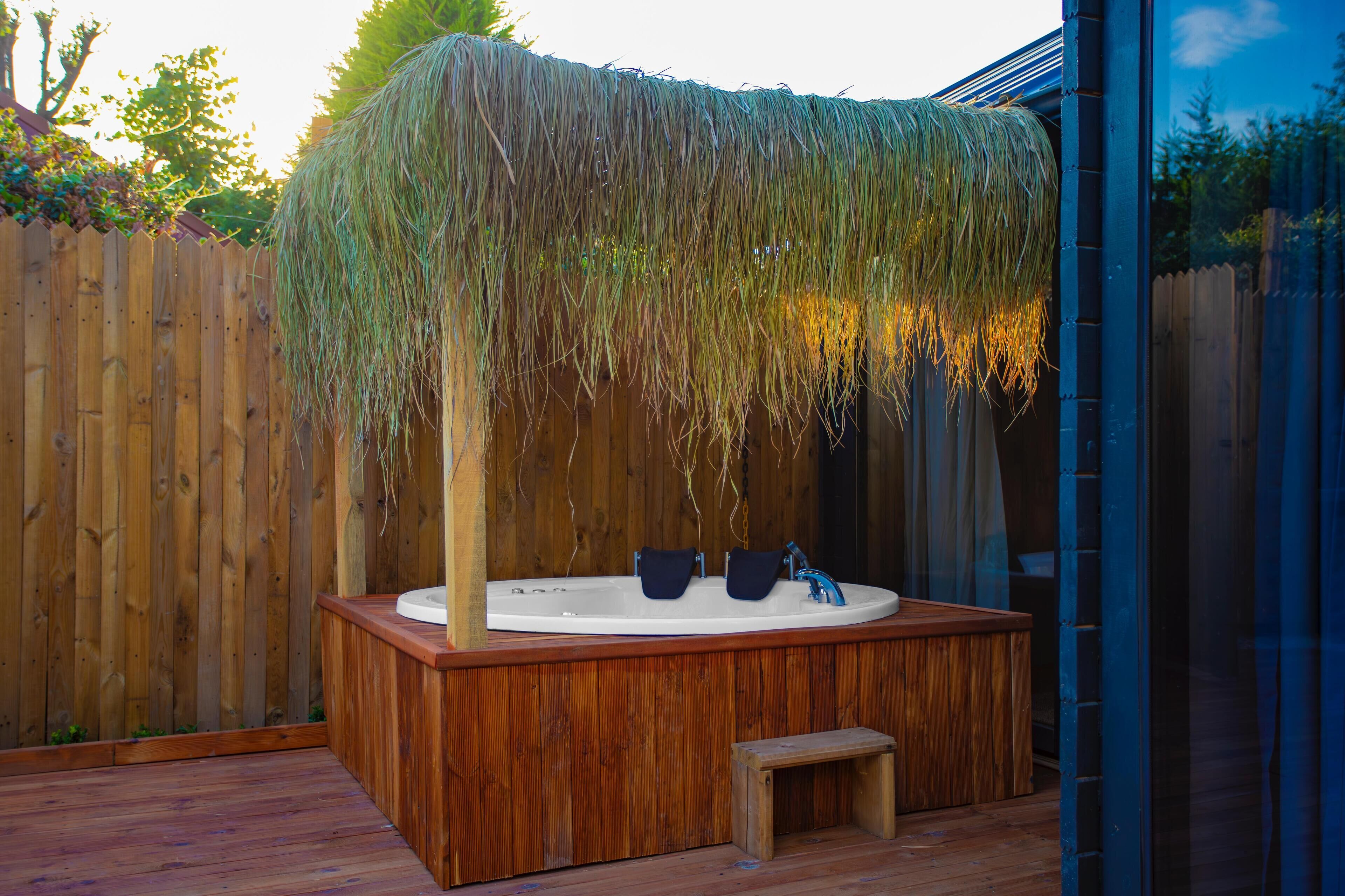 Eine Holzterrasse mit Whirlpool und Sitzbank.