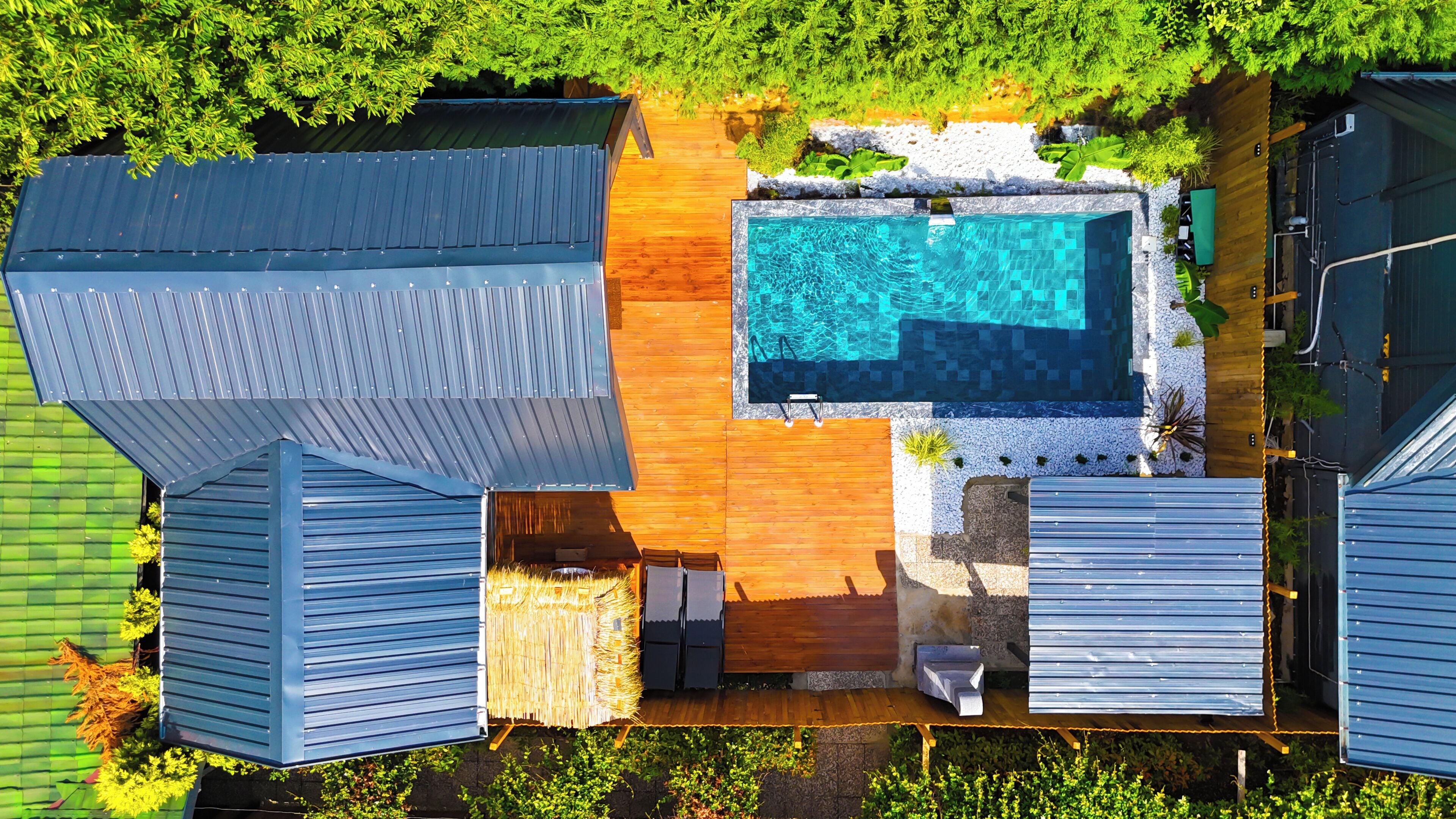 Un área de piscina en la azotea con terraza de madera, piscina y edificios adyacentes.