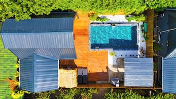 Un área de piscina en la azotea con terraza de madera, piscina y edificios adyacentes.