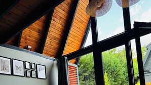 Ein modernes Wohnzimmer mit Holzboden, einem großen Fenster und einem grauen Sofa.