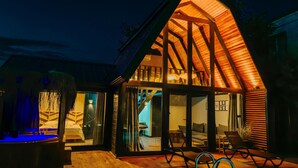 Ein modernes Haus mit Holzfassade, großen Glasüren und einem gemütlichen Innenraum mit Sofa und Essbereich.