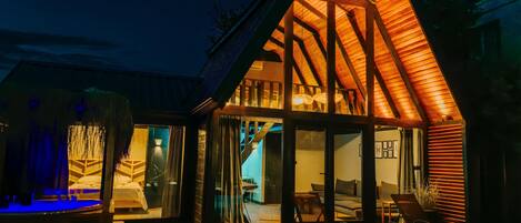 A modern house with a wooden exterior, large glass doors, and a cozy interior with a sofa and a dining area.
