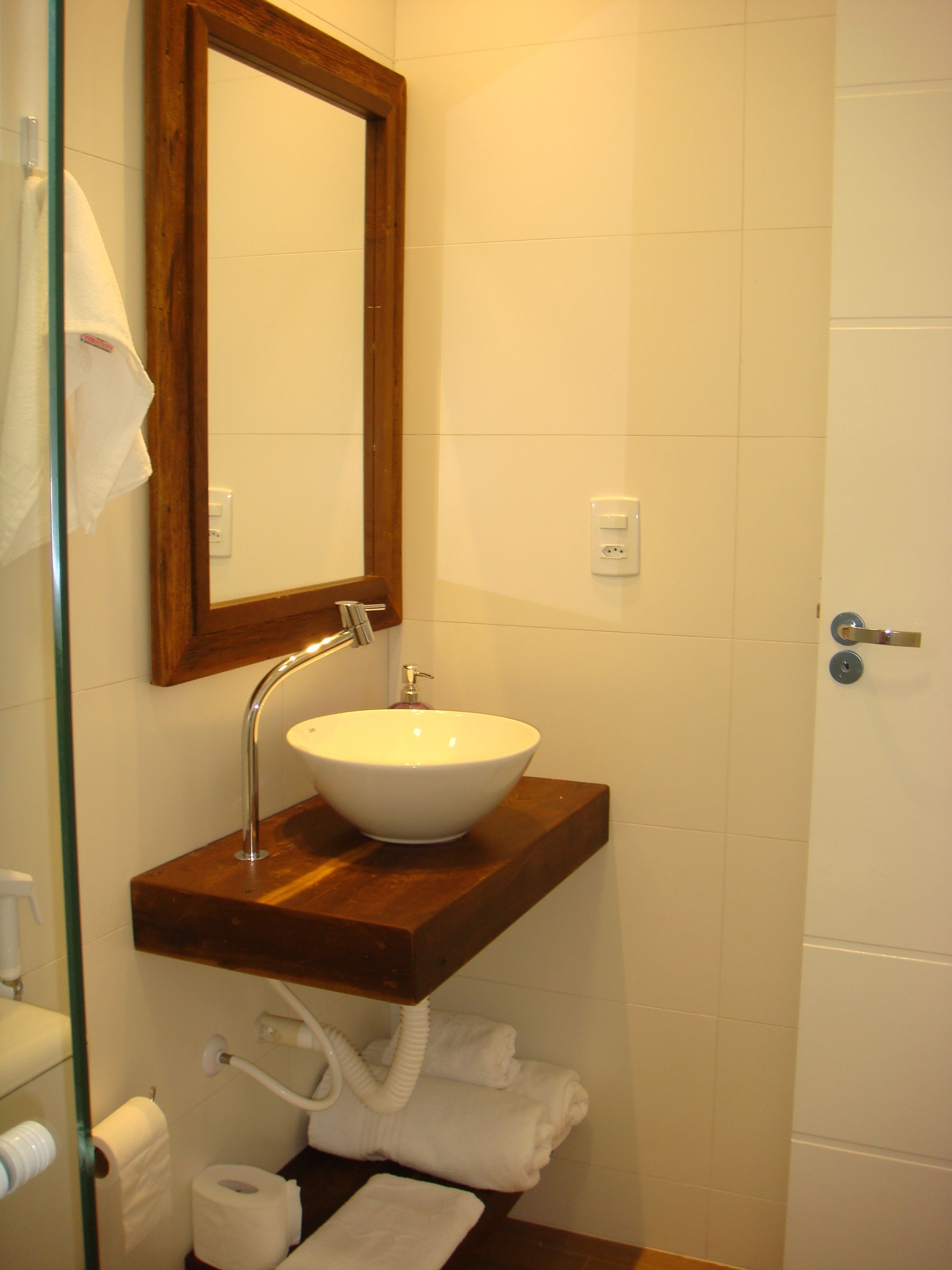 A bathroom with a wooden vanity, a white sink, a mirror, and a towel rack.
