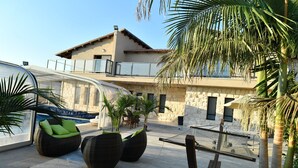 A modern outdoor patio with wicker furniture, a pool, and a stone building in the background. - Shlomo Cabins Boutique (Merom HaGalil)