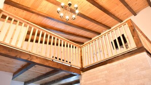 A wooden balcony with a chandelier, exposed beams, and brick walls. - Shlomo Cabins Boutique (Merom HaGalil)